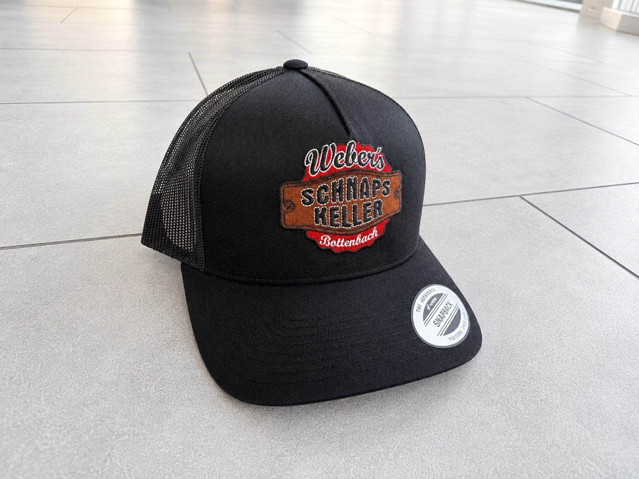 Schwarze Yupoong-Trucker-Caps mit gesticktem Logo-Patch, verpackt in Boxen zur Übergabe